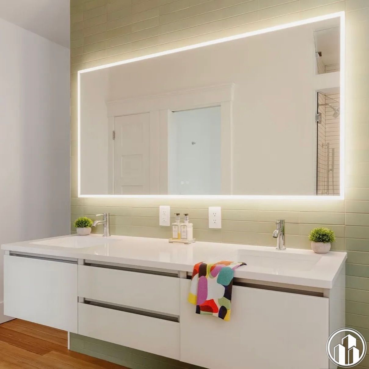 Modern white bathroom vanity with double sinks, lit mirror, and colorful towel accent