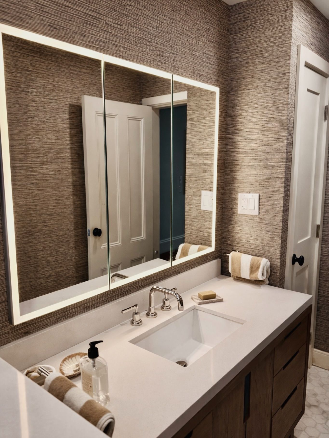 Modern bathroom vanity with a large mirror, white sink, and dark wood cabinets