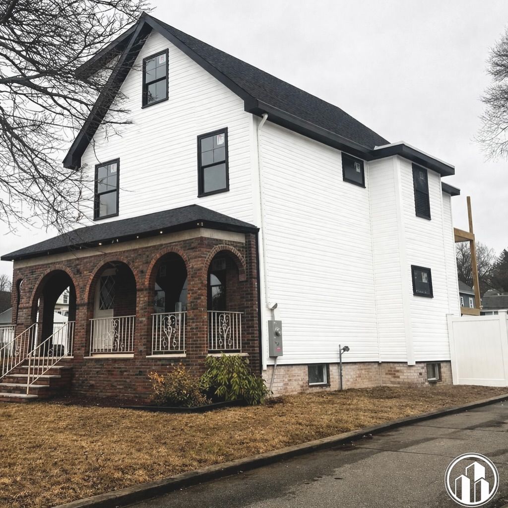 White two-story house with a brick arched porch and black trim on an overcast day