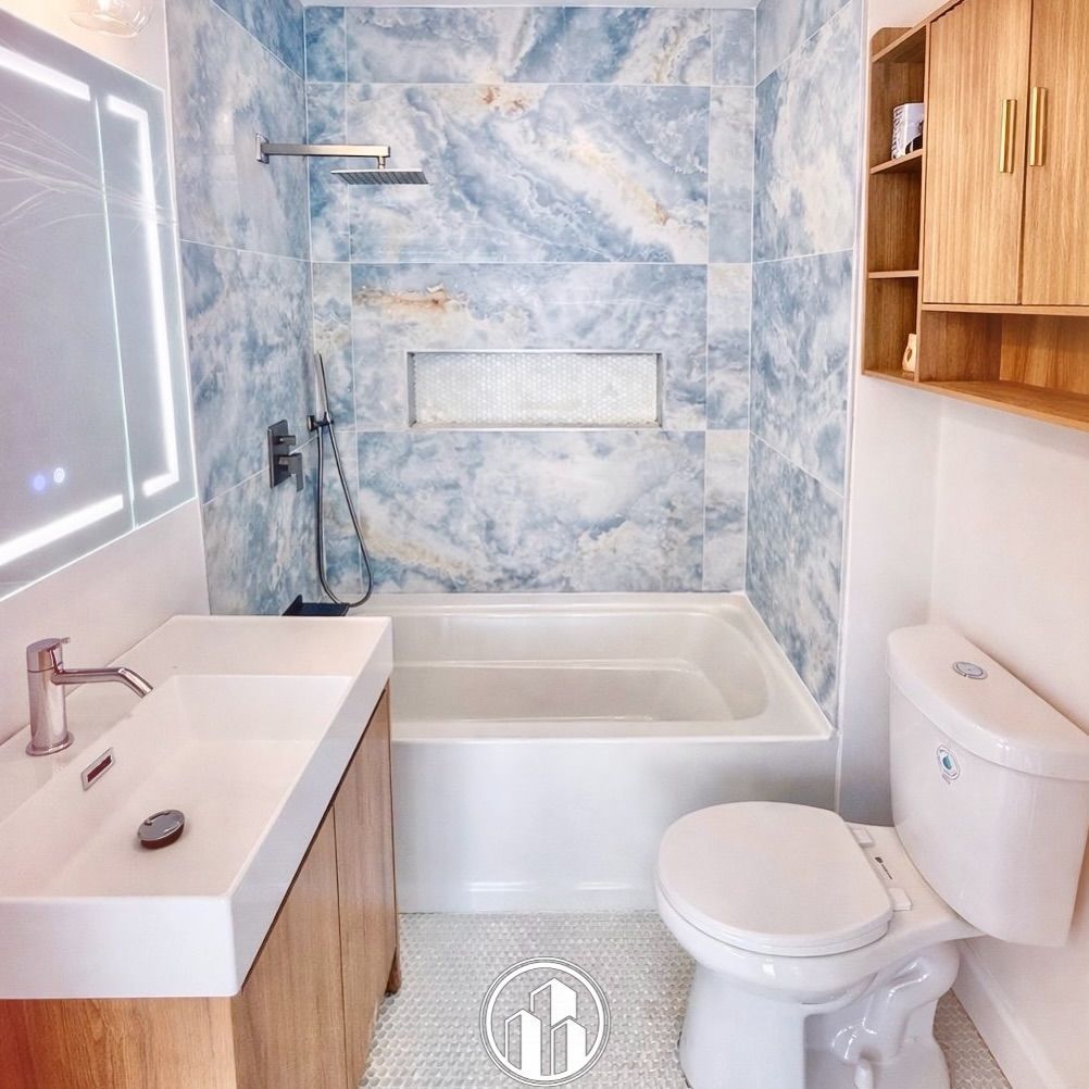 Modern bathroom with marble shower, white tub, sink, toilet, and wooden cabinets