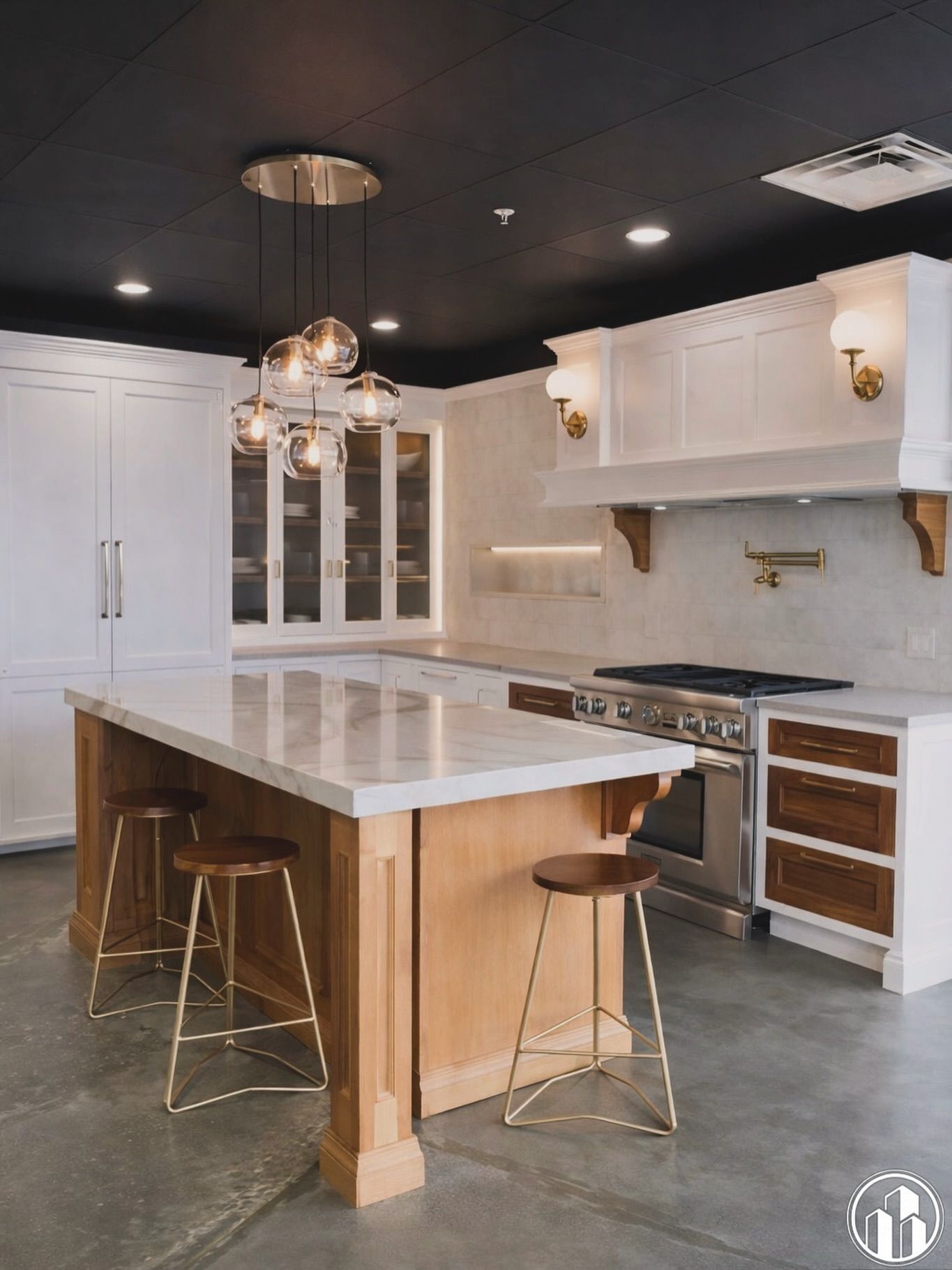 Modern white kitchen with marble island, brass pendant lights, and black ceiling