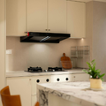 Modern kitchen with white cabinets, marble island, black range hood, and two wooden chairs
