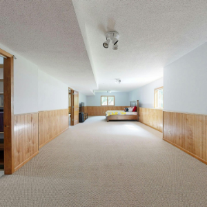 Long carpeted basement hallway with wood-paneled walls and a sitting area at the far end