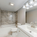 Bright bathroom with white vanity, mirror lights, tiled shower, and bathtub