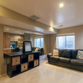 Modern living room with black leather sofa, cube storage bench, and open kitchen area.