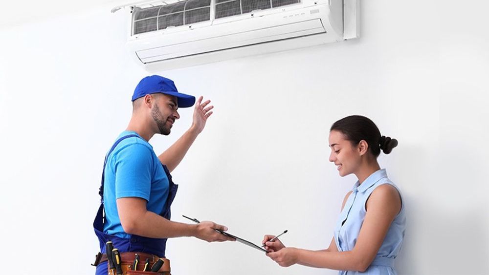 A man and a woman are standing next to each other in front of an air conditioner.