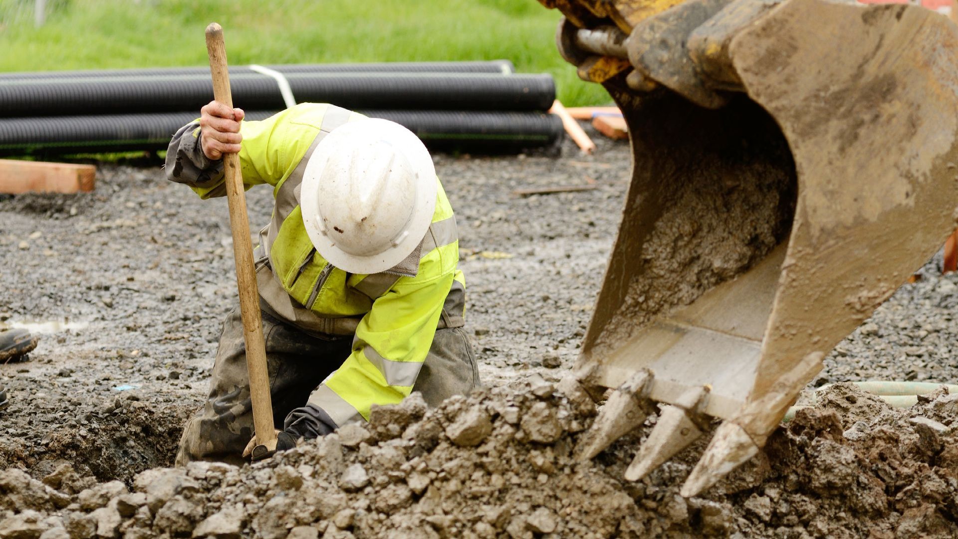 A construction worker is digging in the dirt with a shovel.