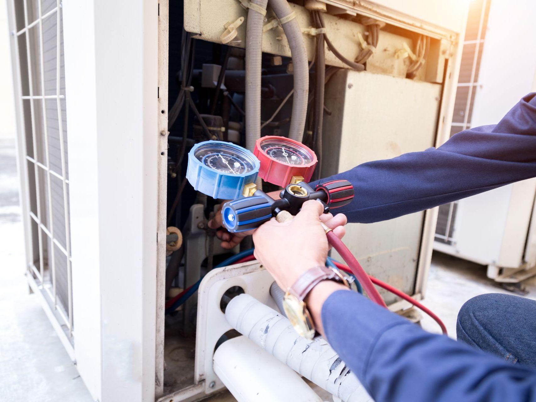 A man is working on an air conditioner with a tool.
