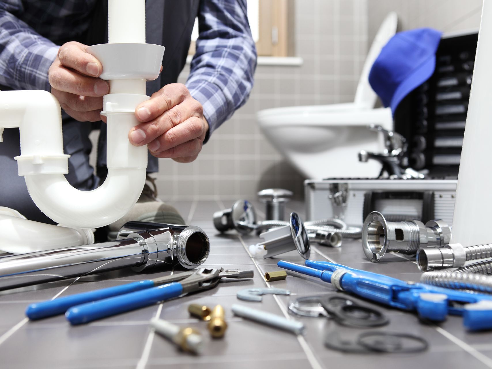 A plumber is working on a pipe in a bathroom.