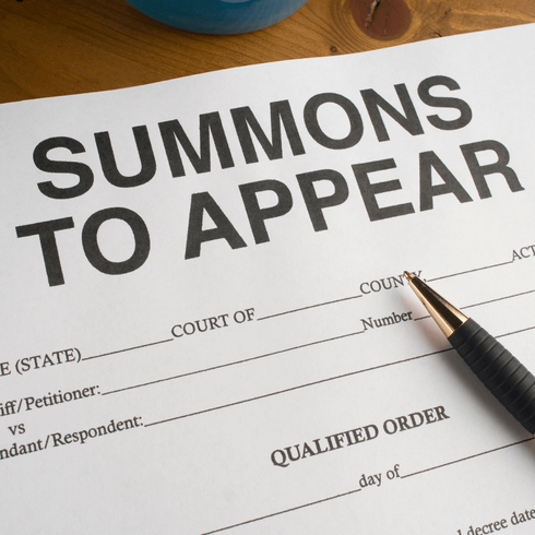 A summons to appear form with a pen on it