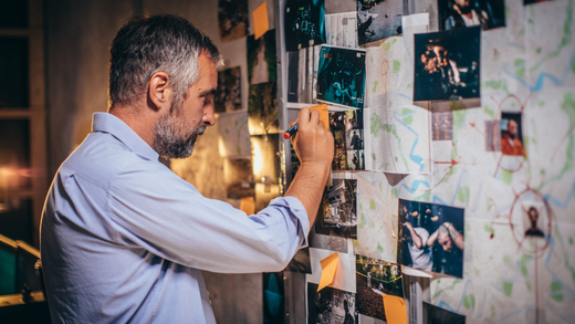 A man is looking at pictures on a wall.