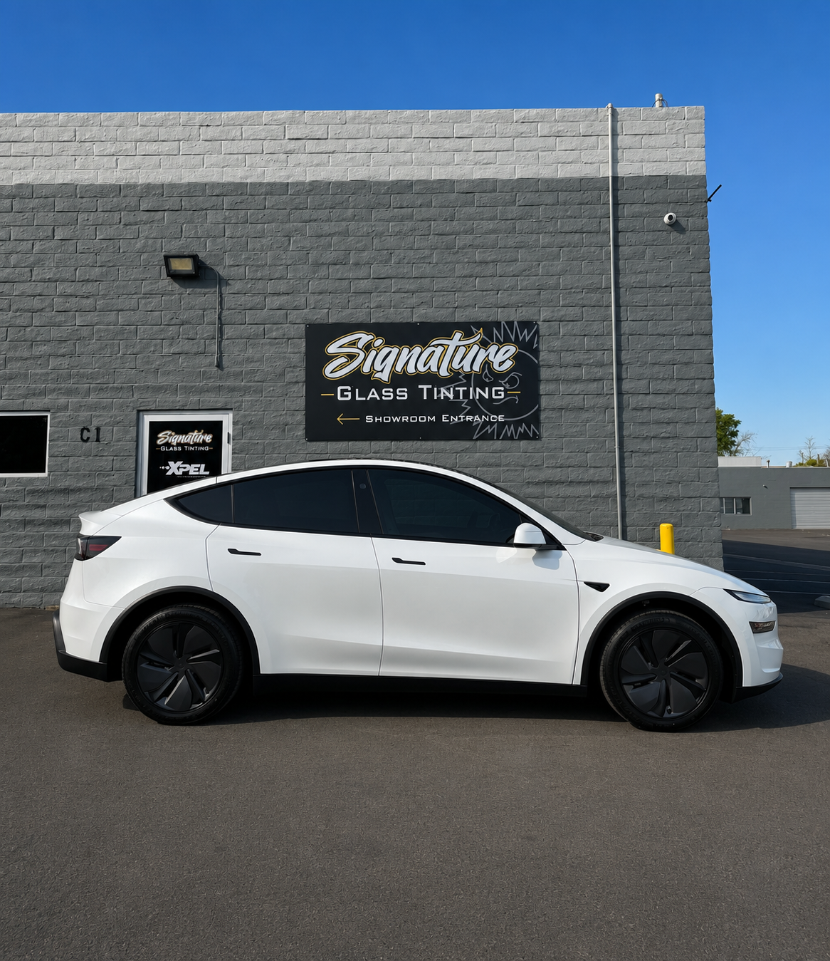 Gray sports car parked outside Signature’s Garage & Tire shop on a brick building.