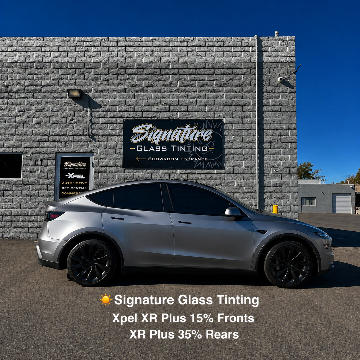 Silver Tesla SUV parked outside Signature Glass Tinting building with text promoting Xpel XR Plus window tint.