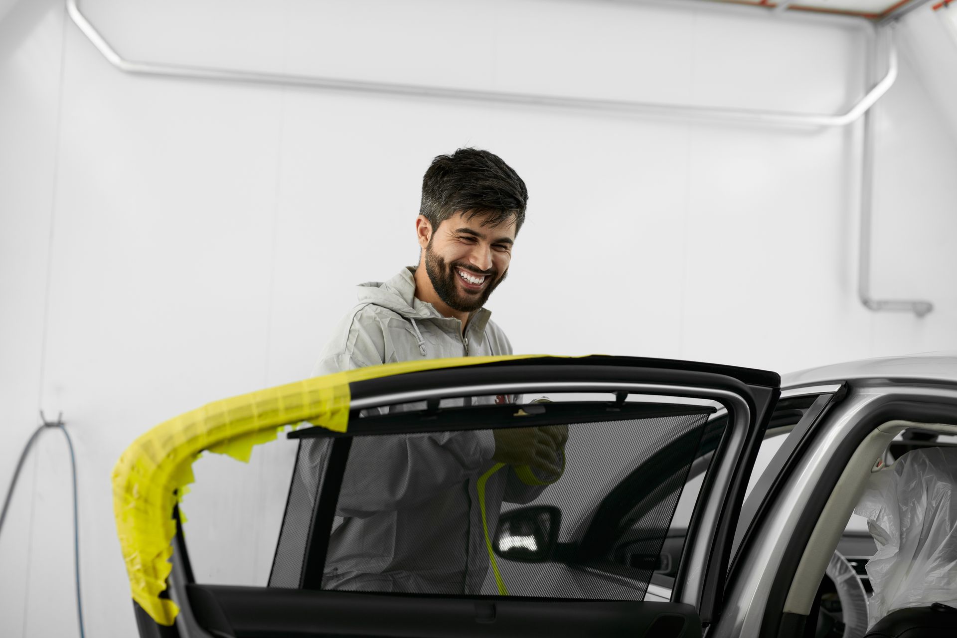Young caucasian mechanic man paste the scotch tape into the vehicle's or car's surface.