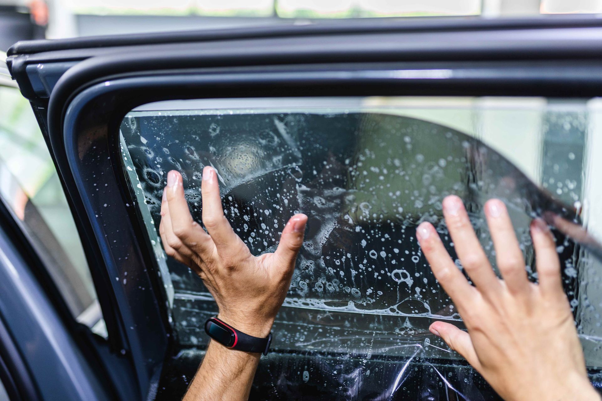 Hands pressed against a car window covered in shattered glass and water droplets