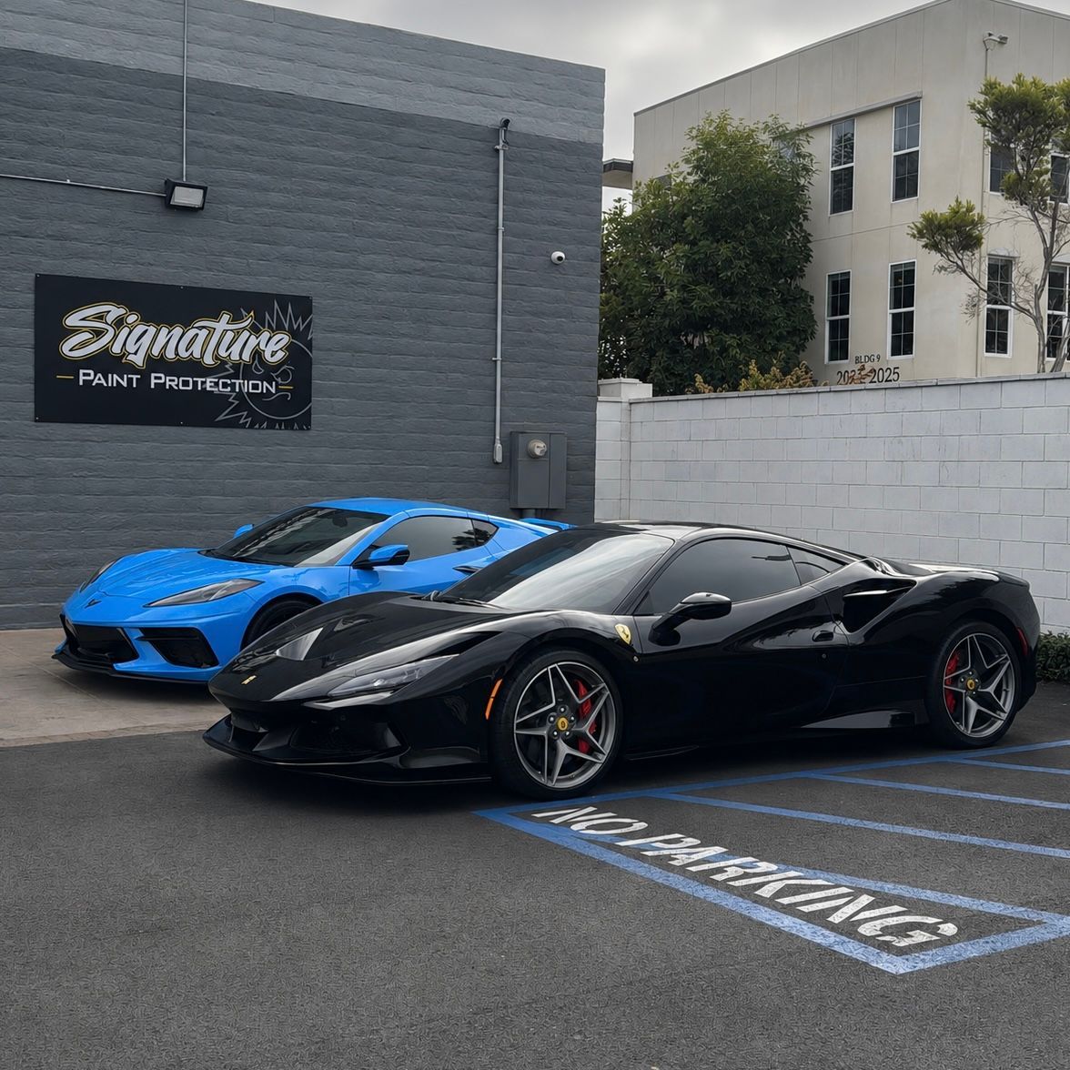 Black and blue sports cars parked outside a performance shop building