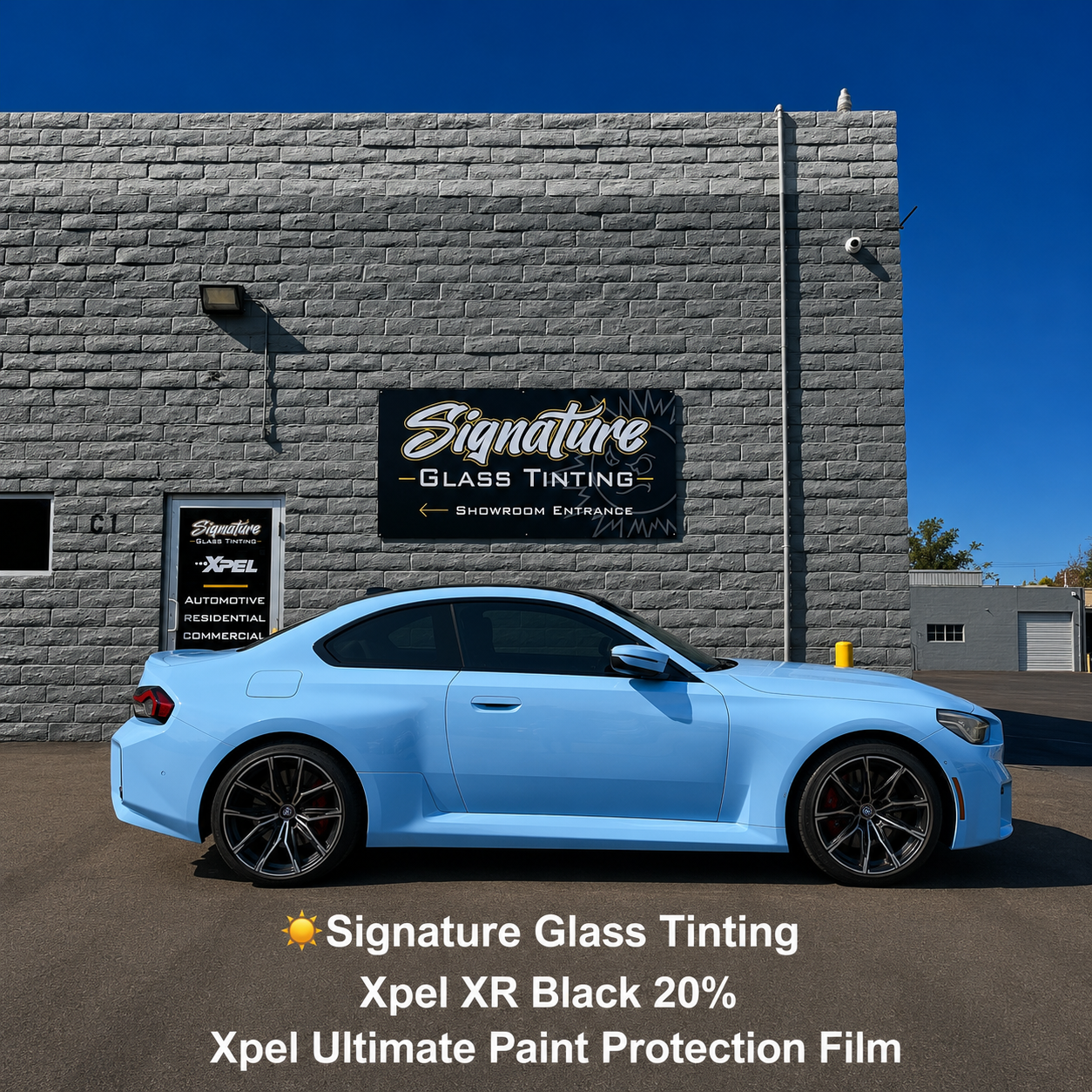 Light blue sports car parked outside Signature Glass Tinting shop with black text on wall