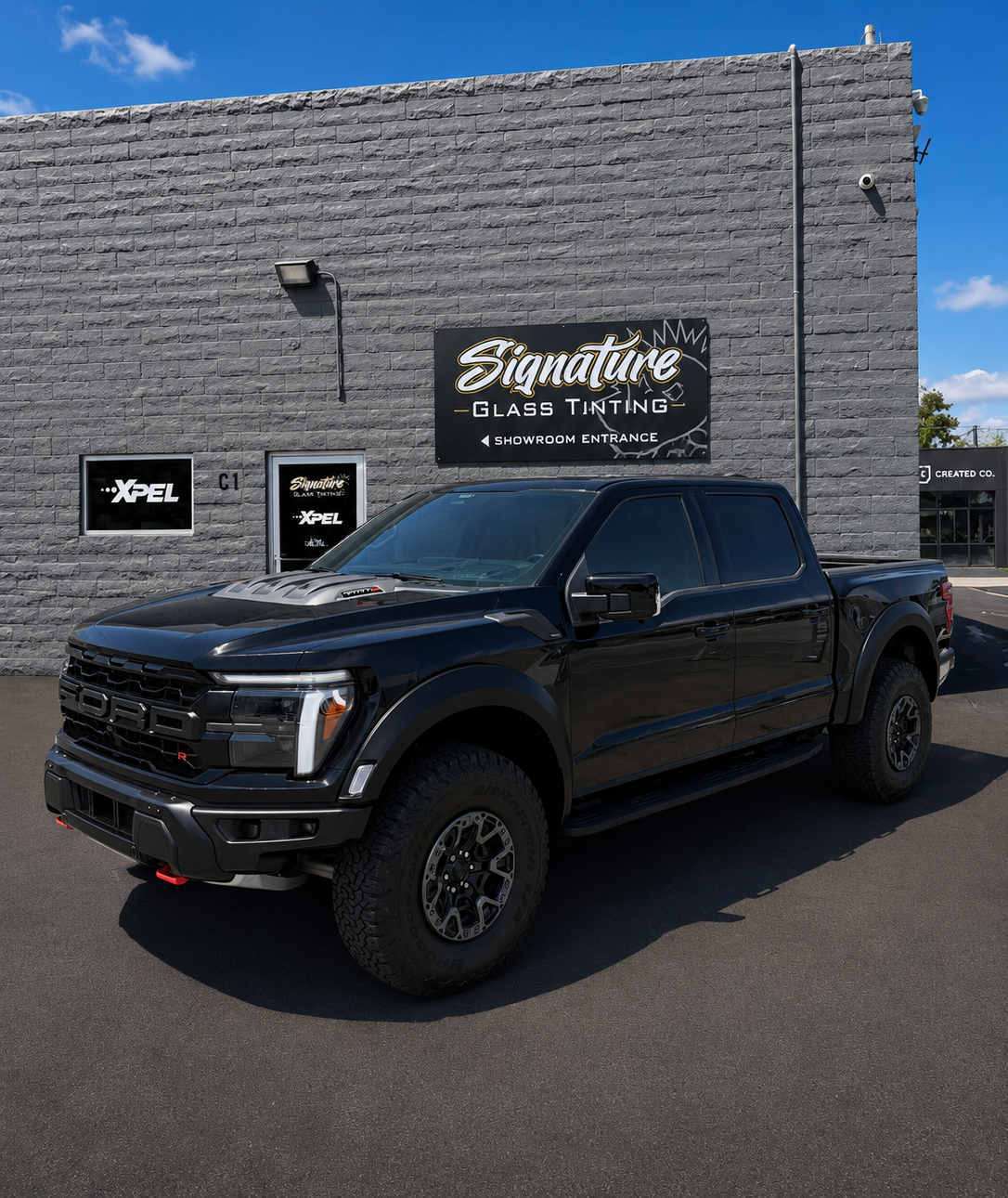 Black pickup truck parked outside a brick building with a Signiture sign above the entrance.