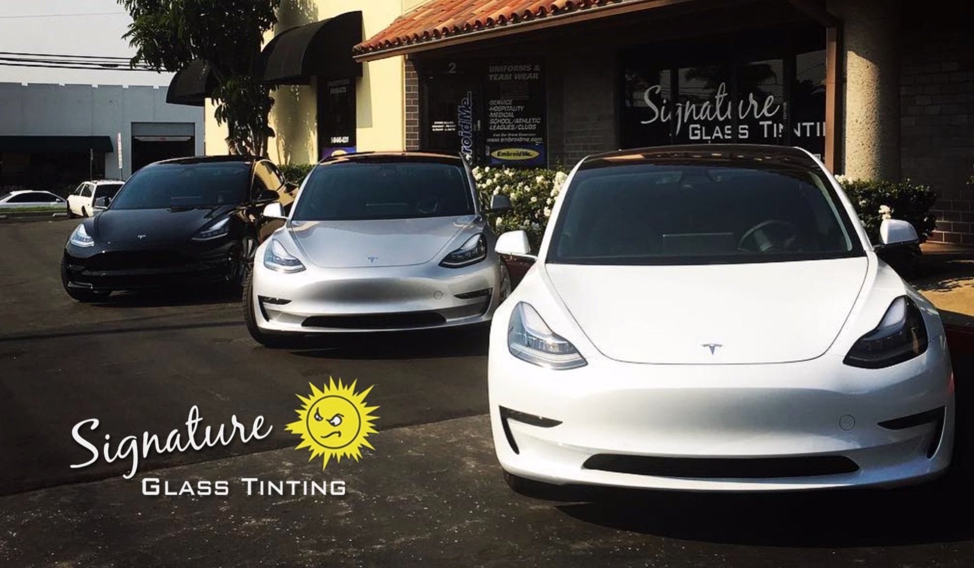 Three Teslas parked outside Signature Glass Tinting shop, with logo on building and lower left corner