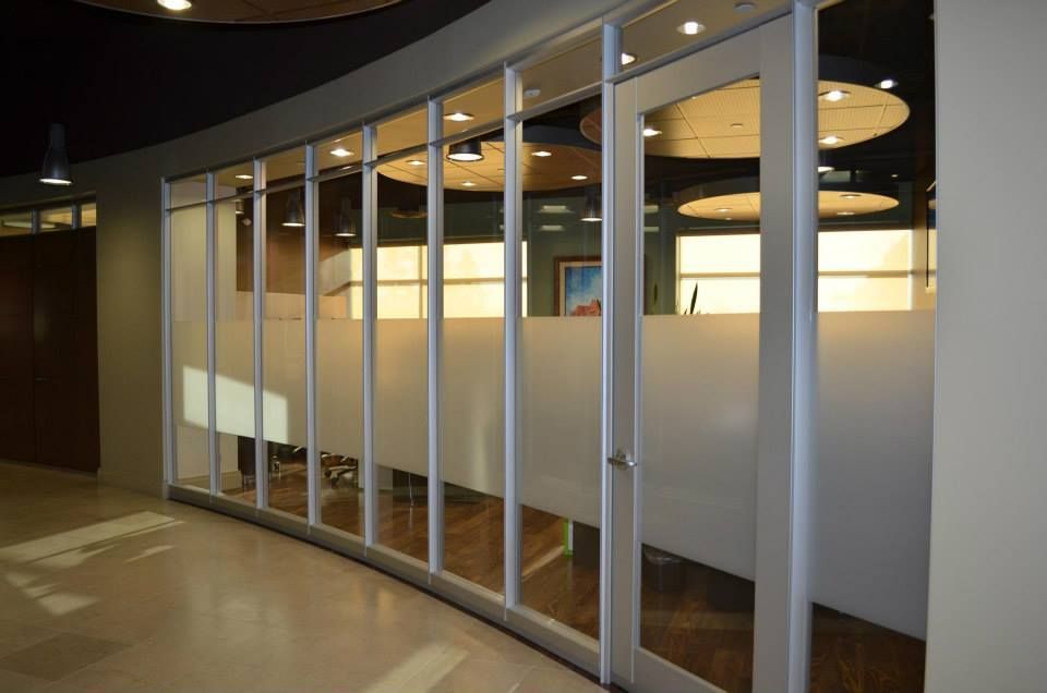 Glass-walled office conference room with frosted panels and curved ceiling lights