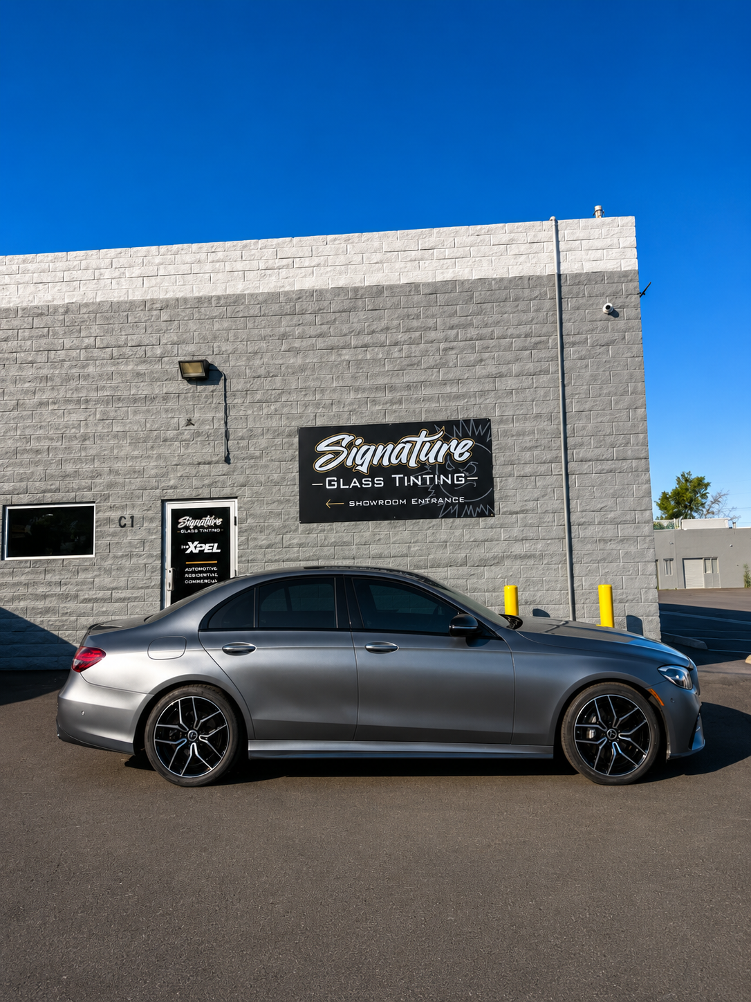 Gray sports car parked outside Signature’s Garage & Tire shop on a brick building.
