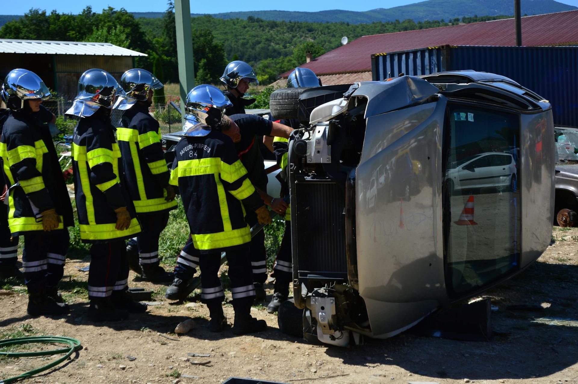 Multiple responders wearing reflector jackets and helmets attending to a car accident scene Multiple responders wearing reflector jackets and helmets attending to a car accident scene