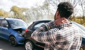 Car accident victim standing near a damaged vehicle, visibly shaken Car accident victim standing near a damaged vehicle, visibly shaken