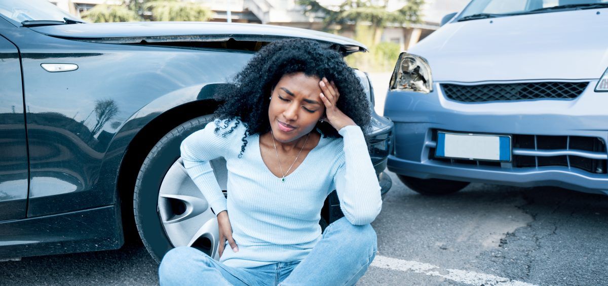 Injured person from a vehicle accident standing near the crash site, visibly in pain