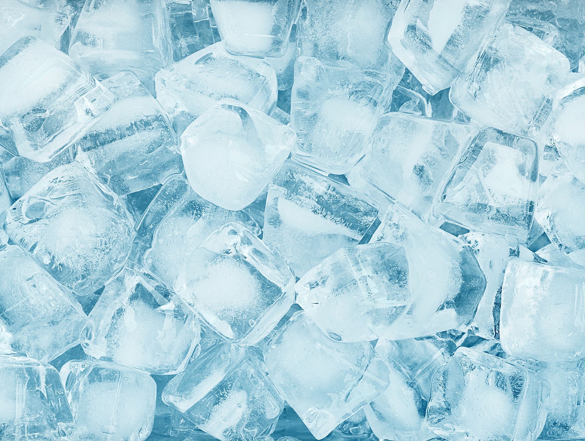 Photograph showing a close-up view of numerous translucent ice cubes with a bluish tint.