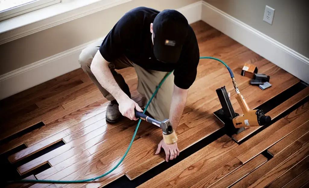A man installing hardwood flooring in a Richland, Washington, bedroom area