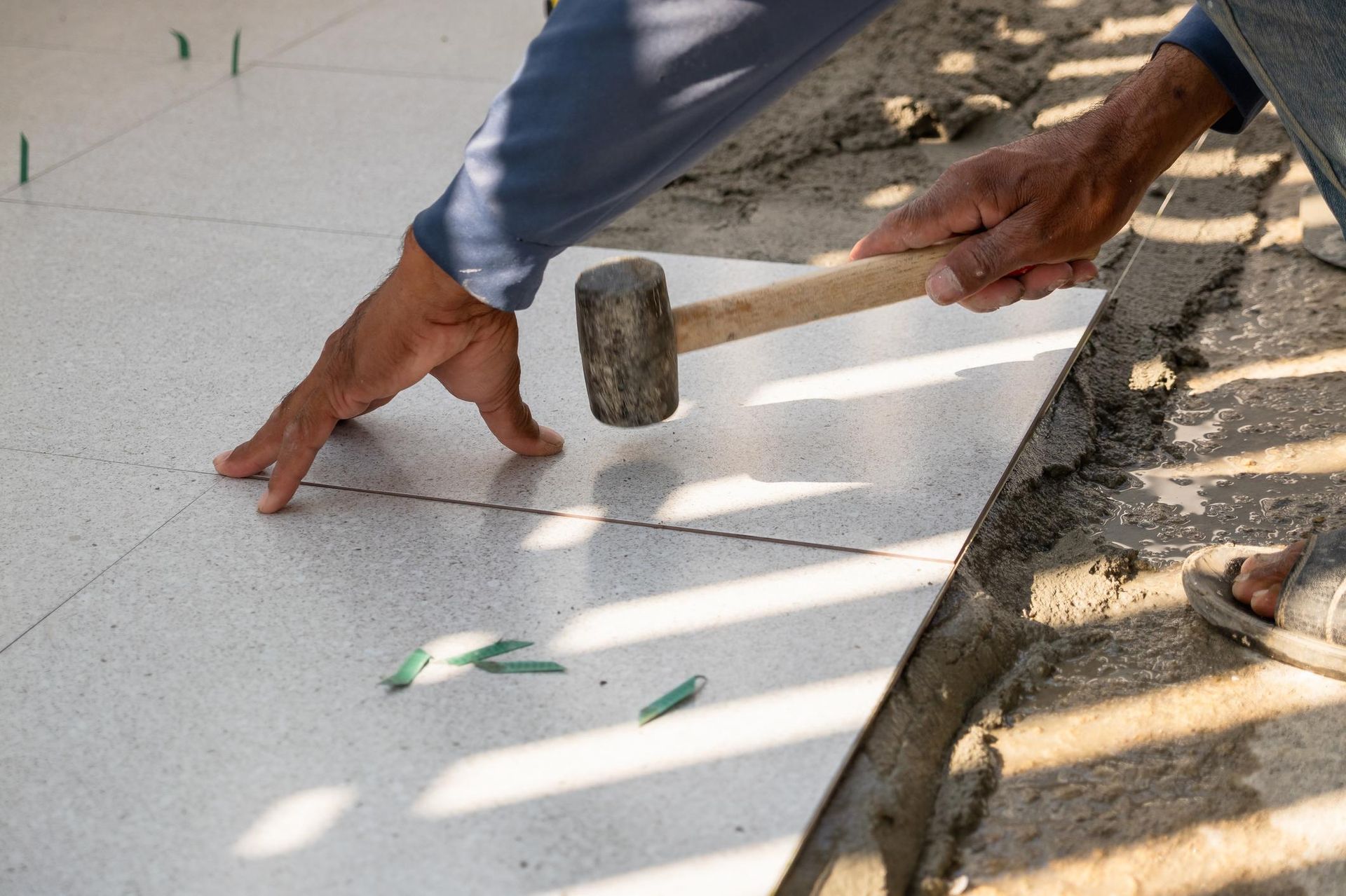 A worker installing tile flooring in a Richland bathroom
