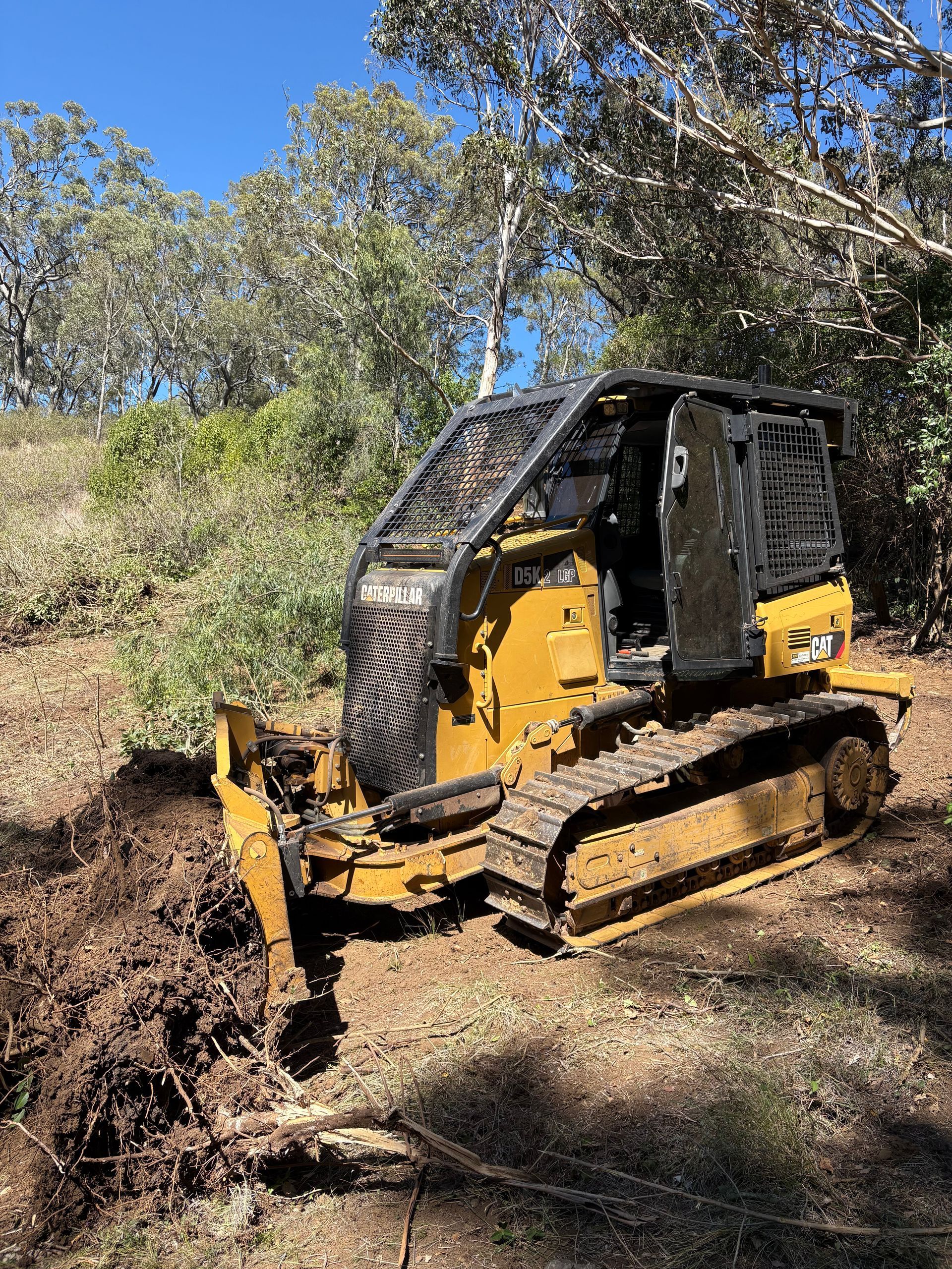 Excavator arm scooping dirt at a construction site, with soil spraying into a pile.