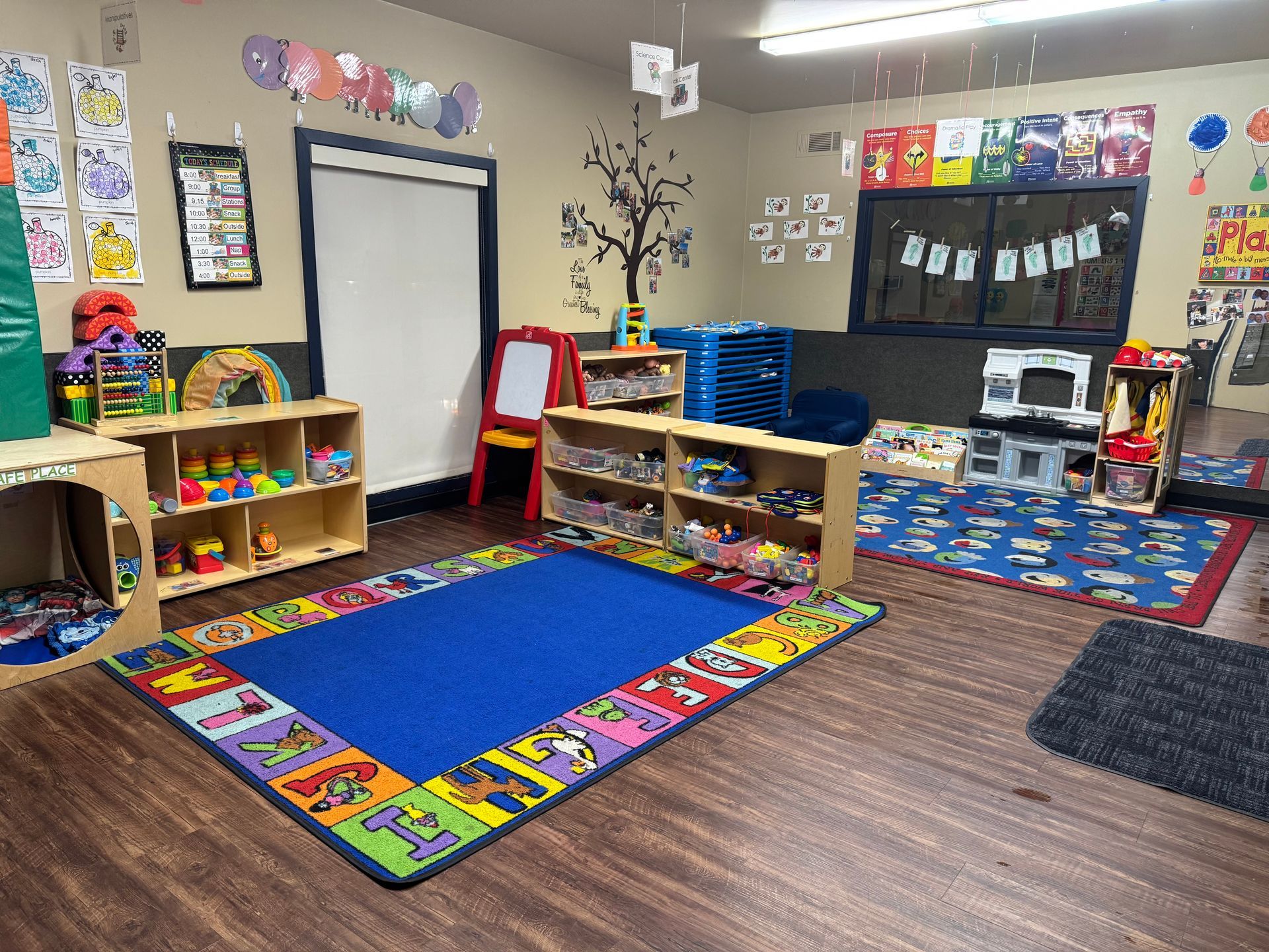 A classroom with toys, a blue rug, and shelves. Colorful decorations adorn the walls.