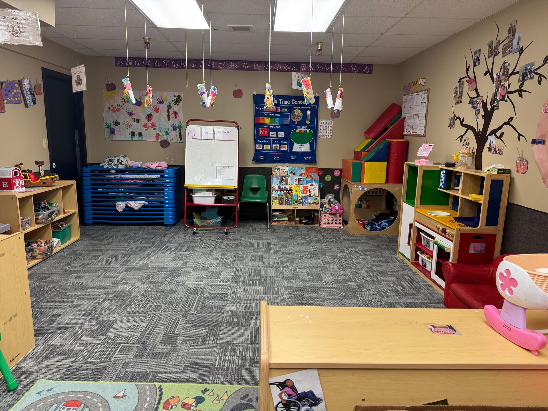 Childcare classroom with toys, play structures, and a whiteboard.