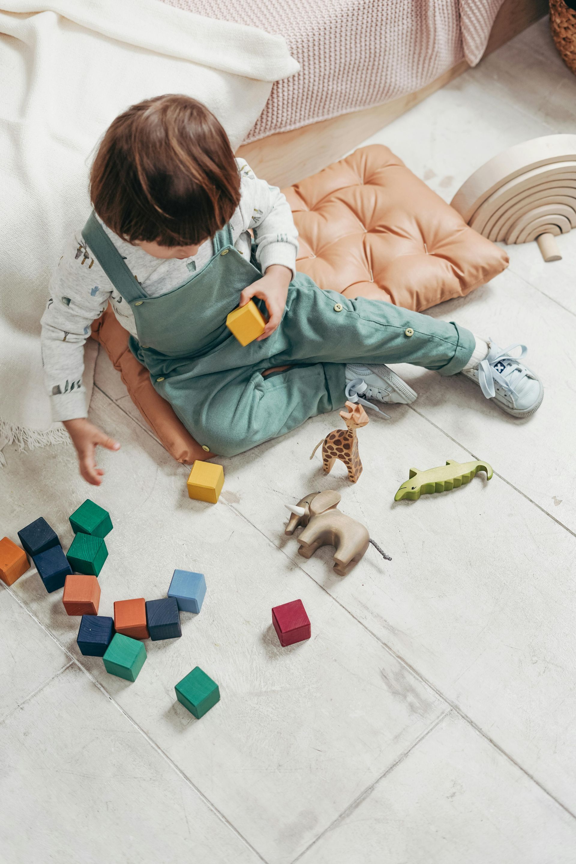 Child playing with colorful blocks and animal toys on a rug.