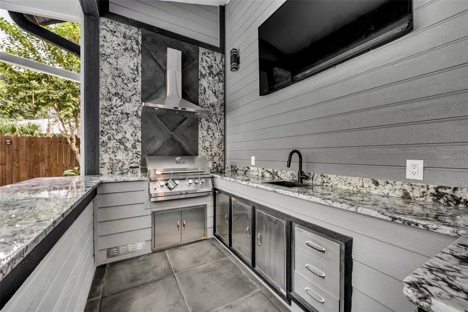 A kitchen with a grill , sink , and television.