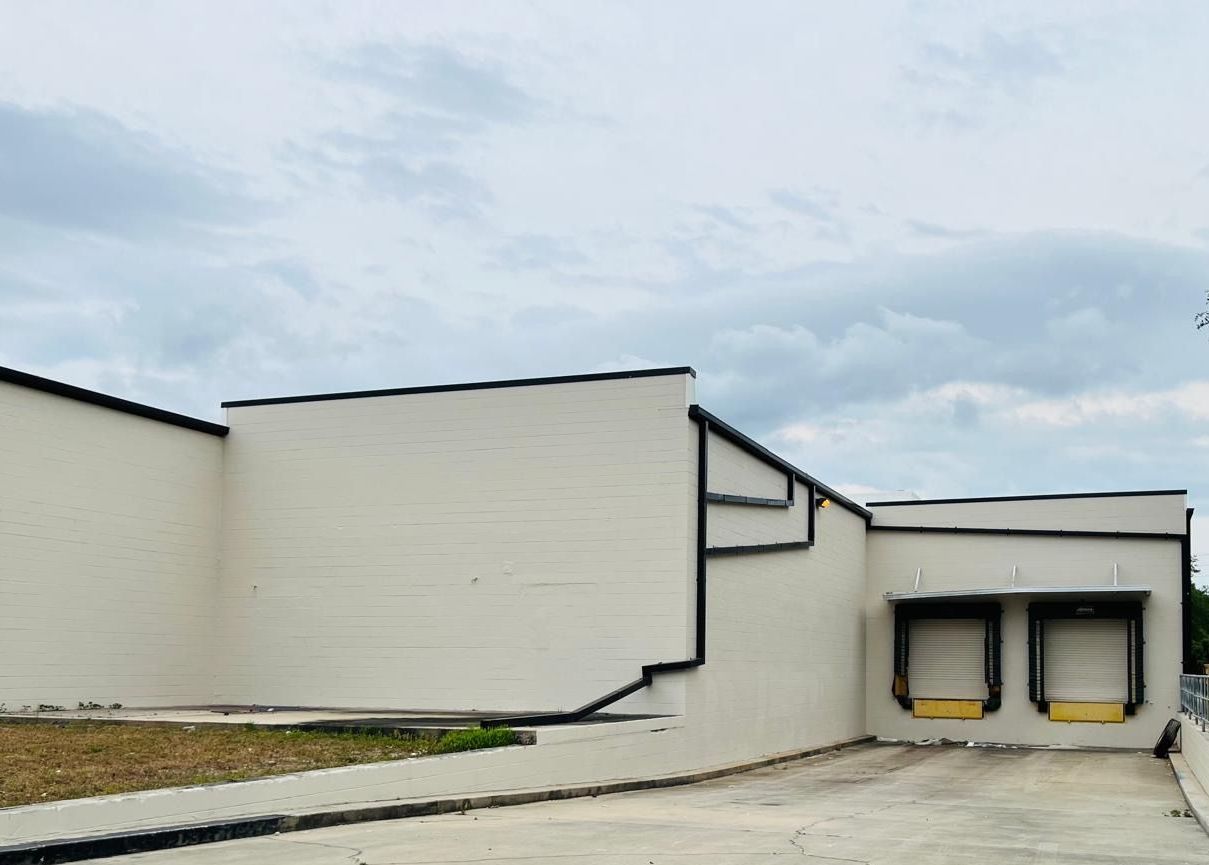 A white building with a loading dock and stairs leading up to it.