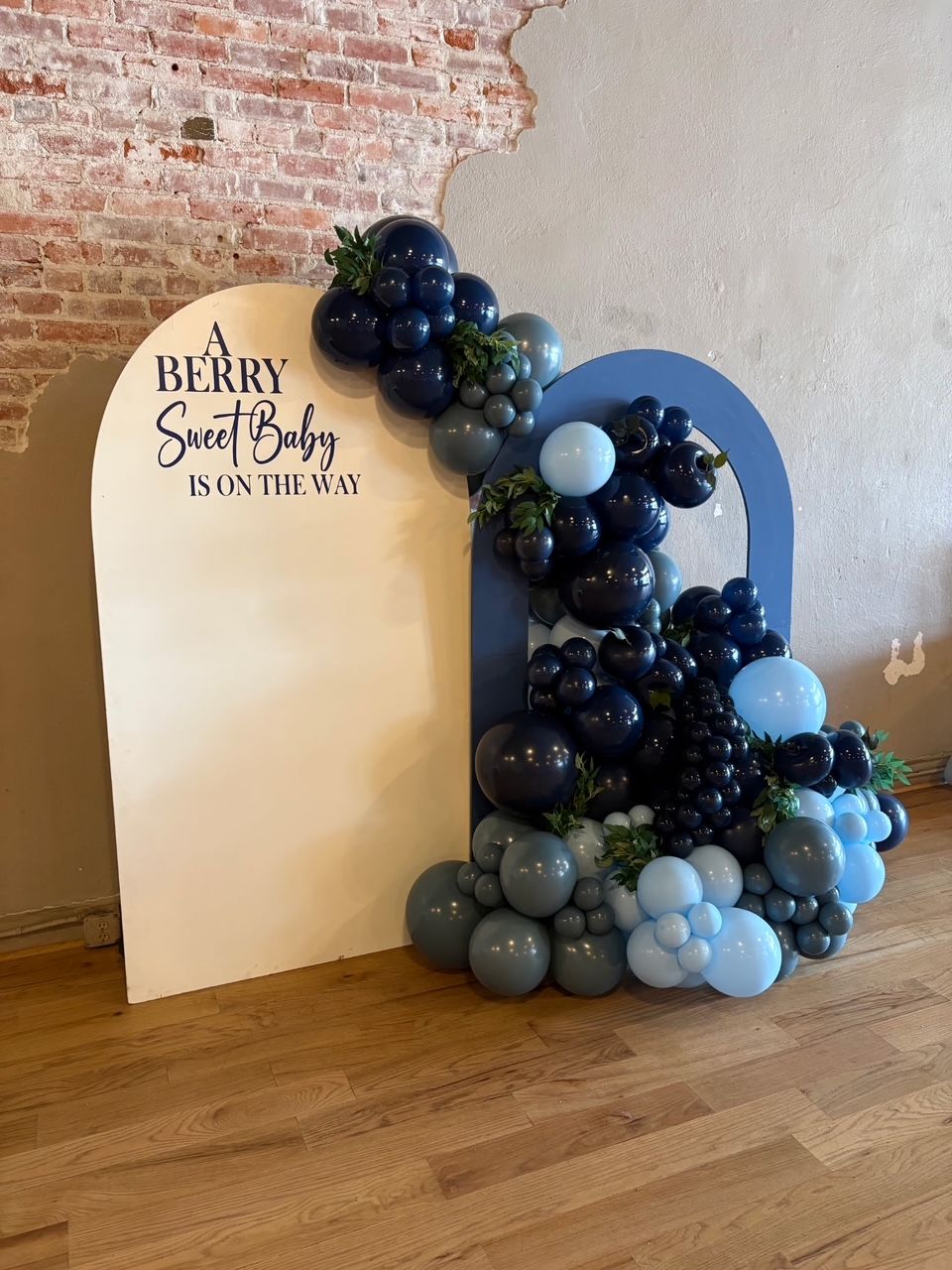Berry Sweet 18th birthday backdrop with blue, gray, and black balloon arch beside a white sign