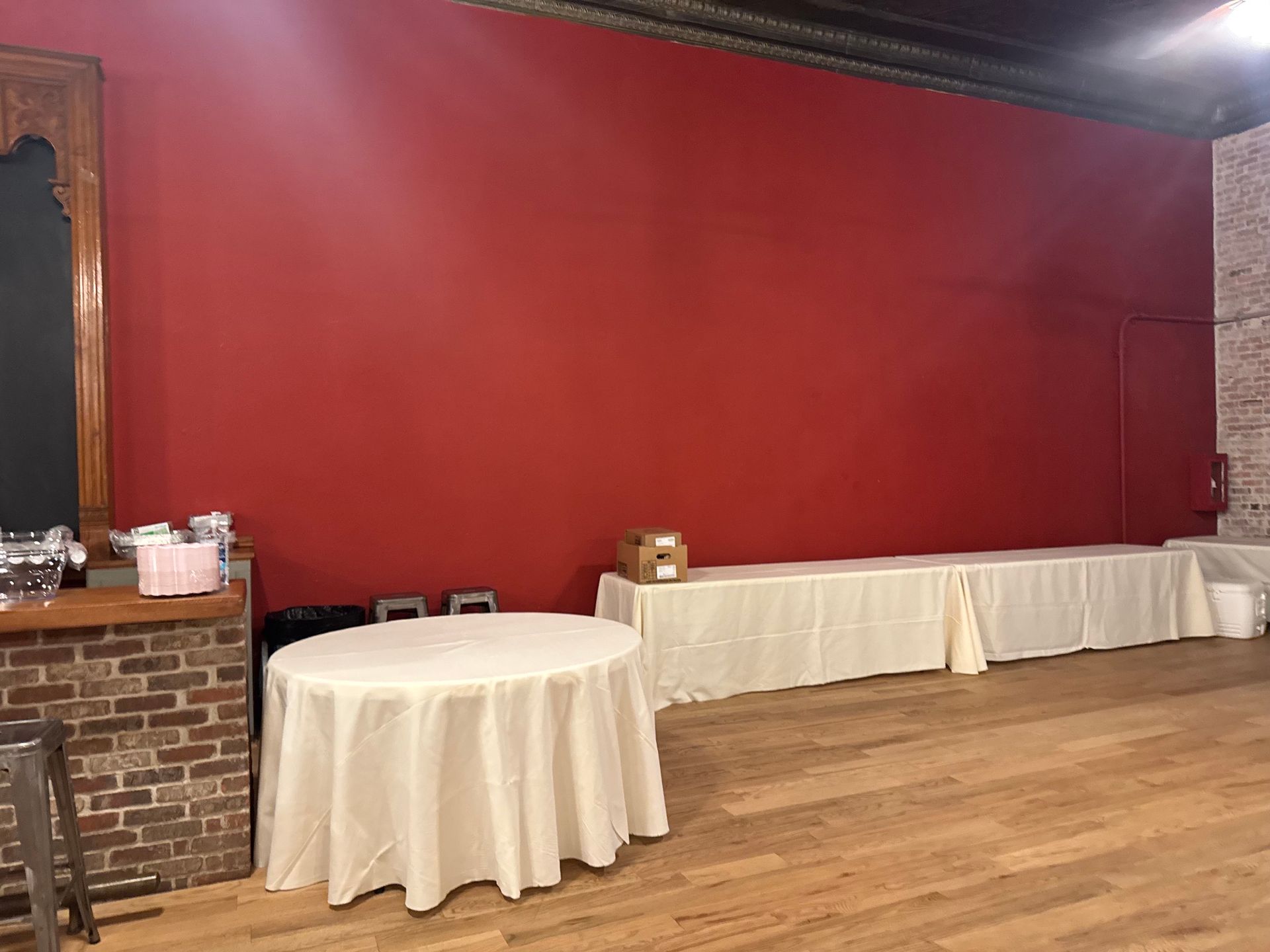 Empty banquet room with red wall, round table, and long buffet table along the side
