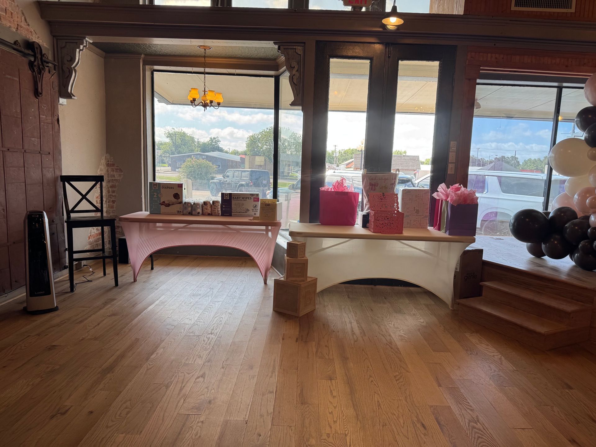 Warm living room with wooden floor, tables by large windows, and mountains visible outside