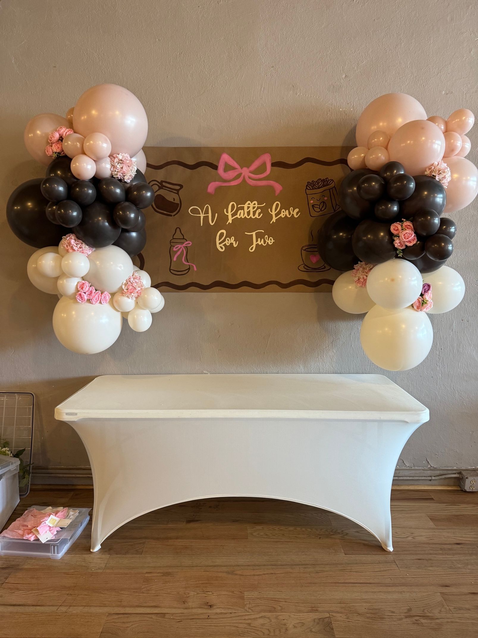 Balloon-decorated dessert table with a white tablecloth and a welcome sign against a wall
