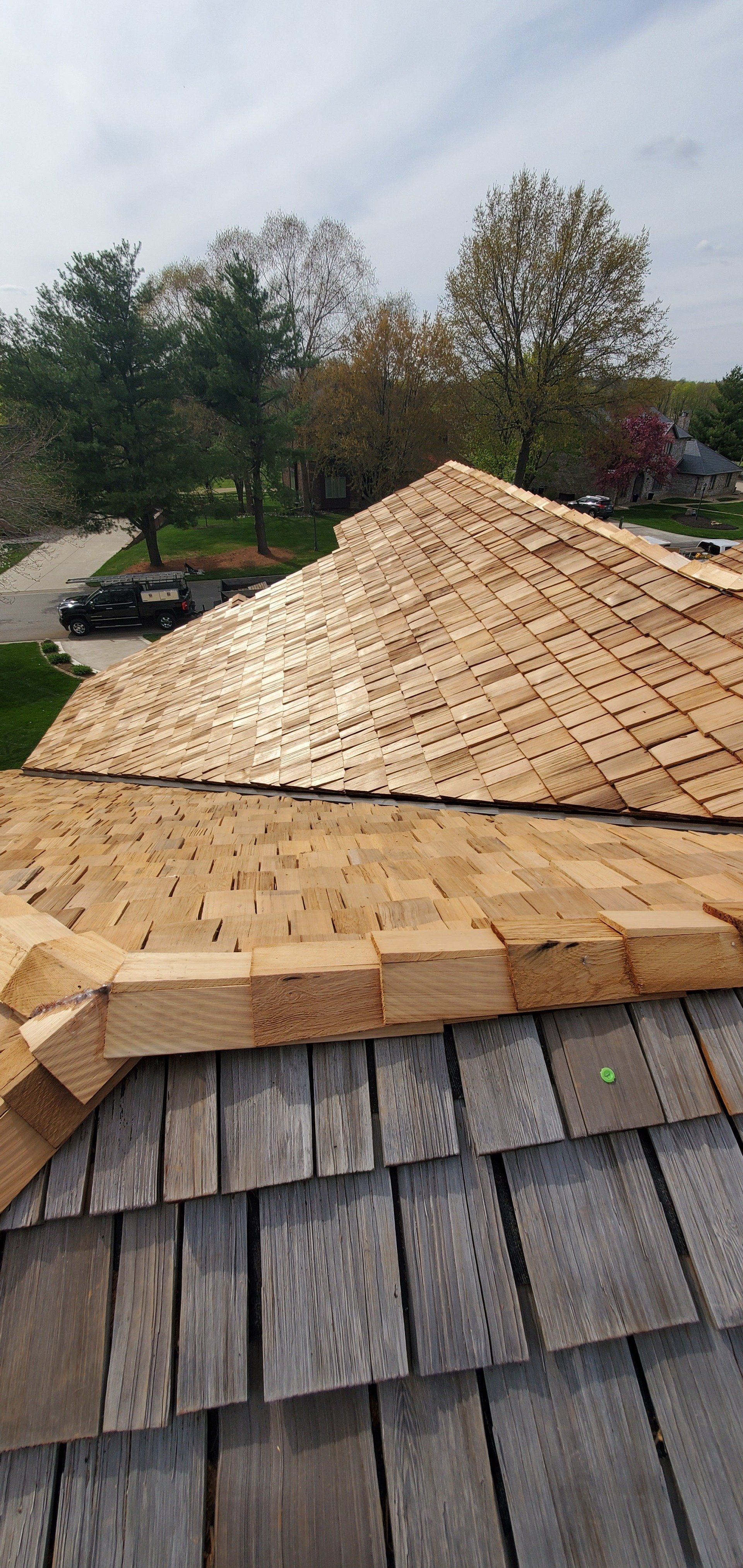 New roof shingles being installed on a house, with trees and a yard in the background