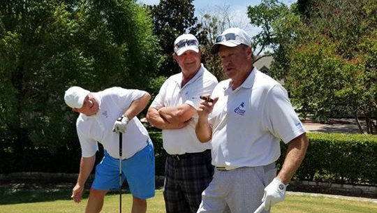 Three men are standing next to each other on a golf course.