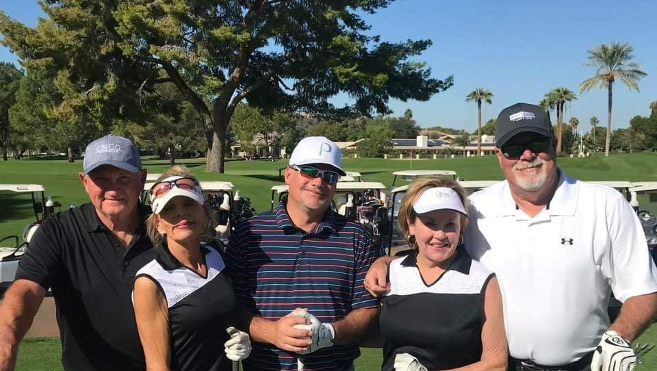 A group of people are posing for a picture on a golf course.