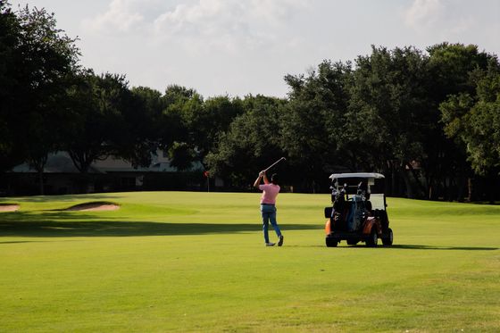 A man is swinging a golf club on a golf course