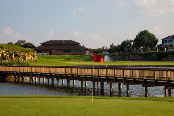 A bridge over a body of water leading to a golf course.