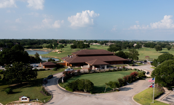 An aerial view of a golf course with a house in the foreground.