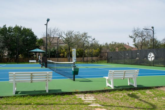 A tennis court with two white benches in front of it
