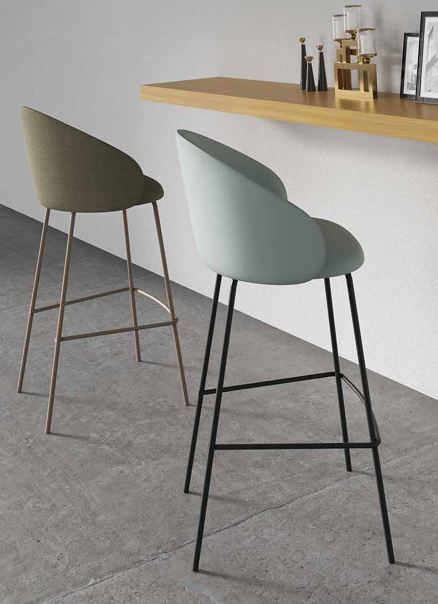 Due sgabelli da bar moderni, color oliva e menta, accanto a un bancone in legno in una stanza minimalista.