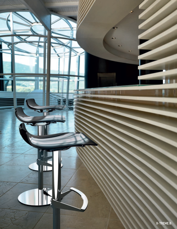 Sgabelli da bar moderni accanto a un bancone della reception bianco e curvo in una luminosa hall con pareti in vetro.